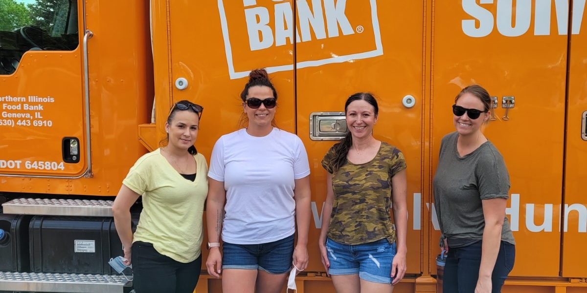 4 women standing in front of an orange Northern Illinois Food Bank truck